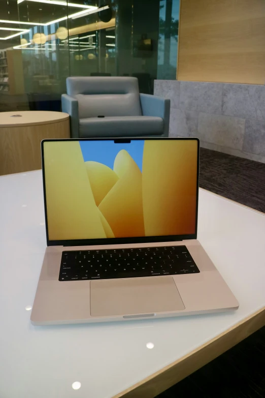 an open laptop sitting on a table with a chair