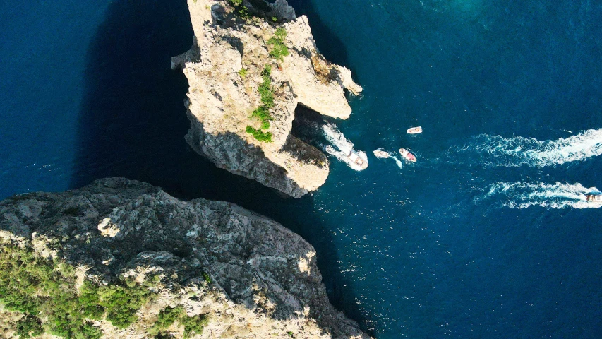 two boats in the ocean near some rocky cliffs