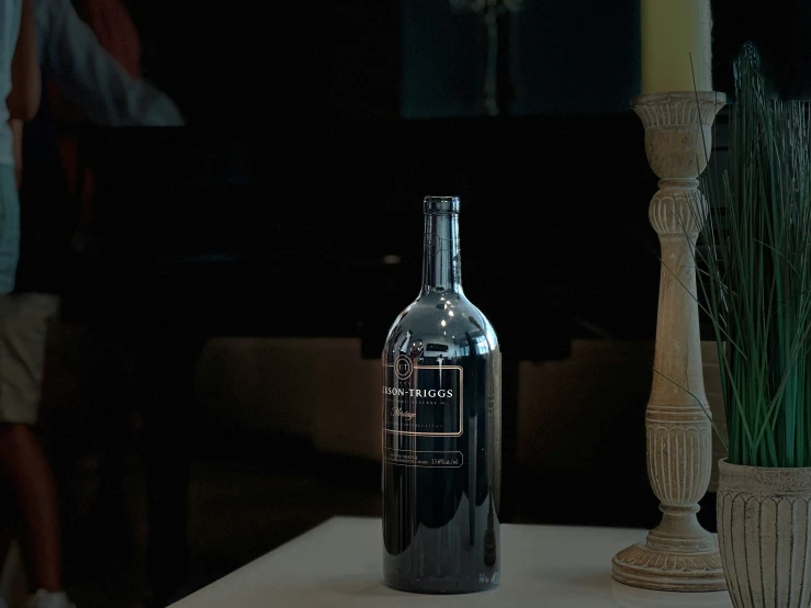 a bottle on a table with vases and a candle