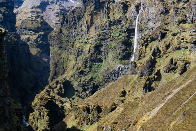 a tall waterfall is nestled in the middle of a mountainside