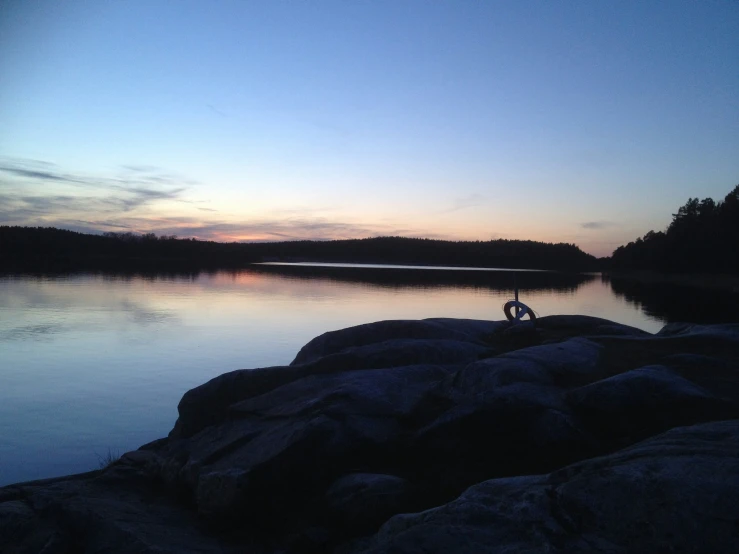 the silhouette of two people on rocks and water