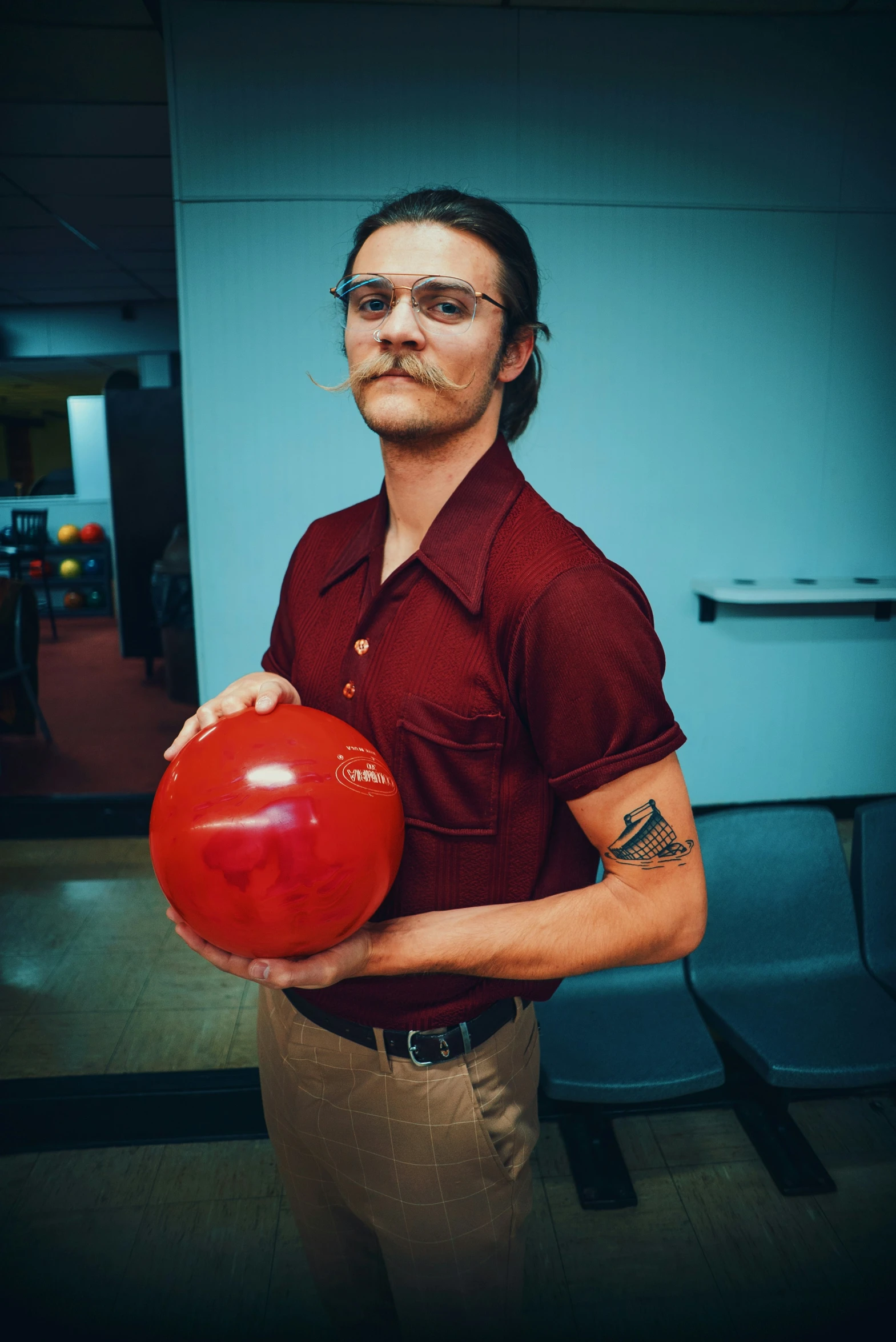 a man with glasses is holding a bowling ball