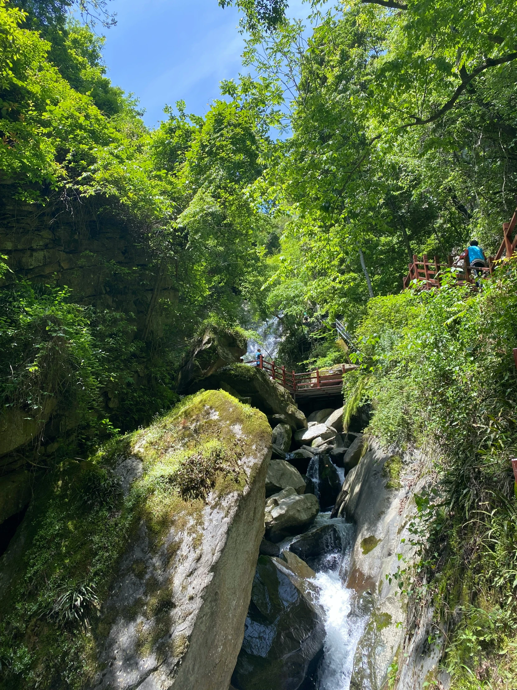 people stand on the rocks above a small waterfall