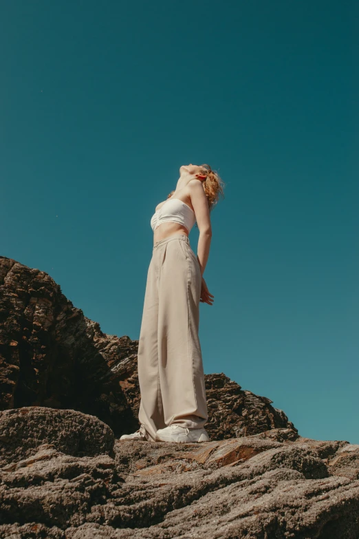 a girl stands on a rock while gazing off in the distance