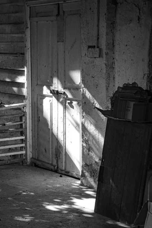 an old shack with a door, open and a trash can in front