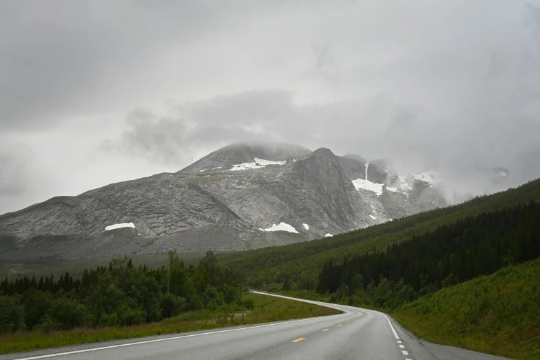 a wide road in the mountains with snow on the mountains