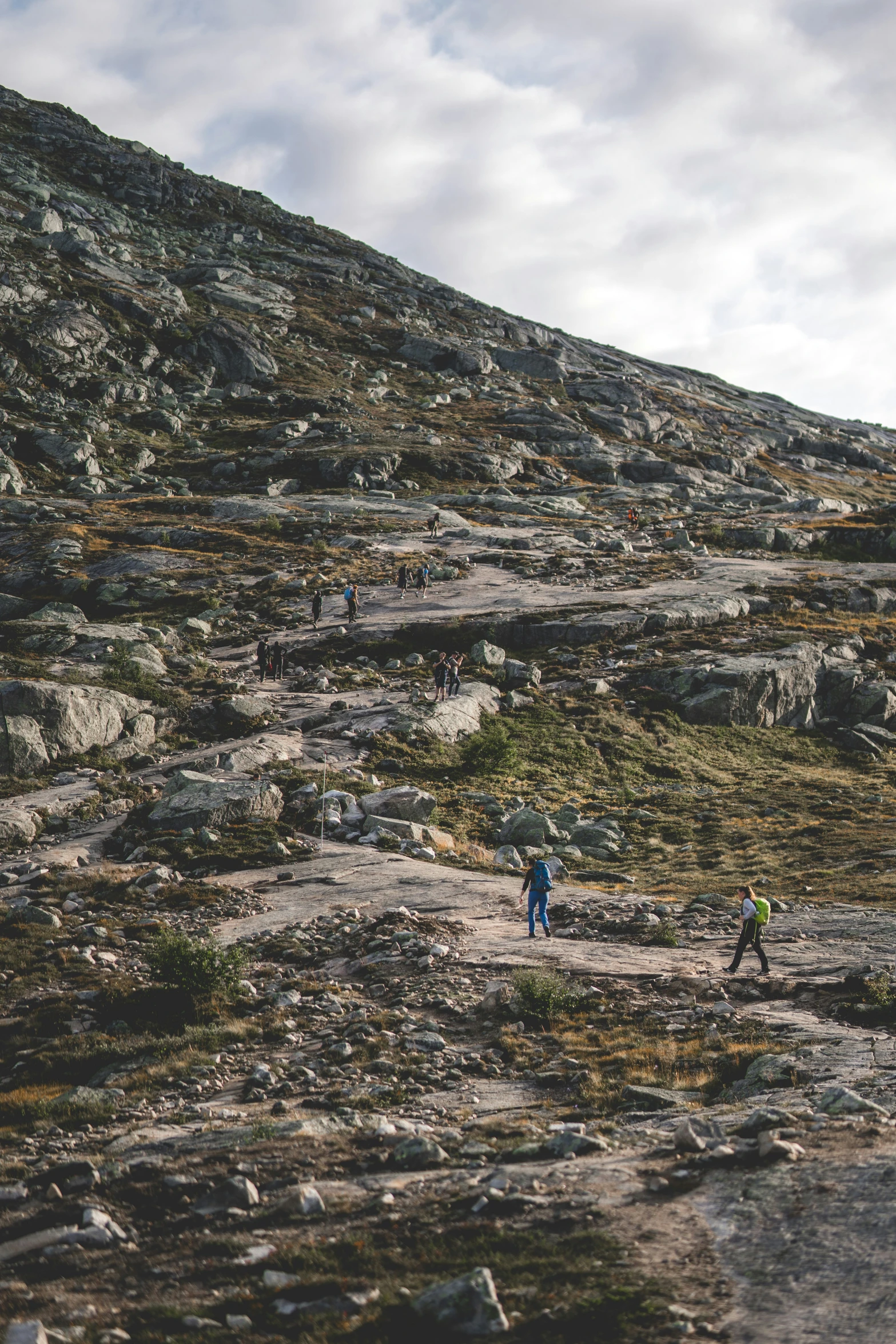 two people walking down the hill of rocks