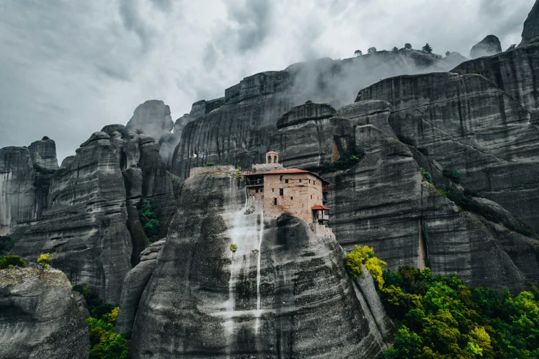 an image of a building on a rock in the mountains