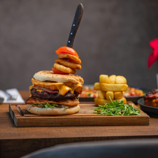 a hamburger and fries stacked on a board