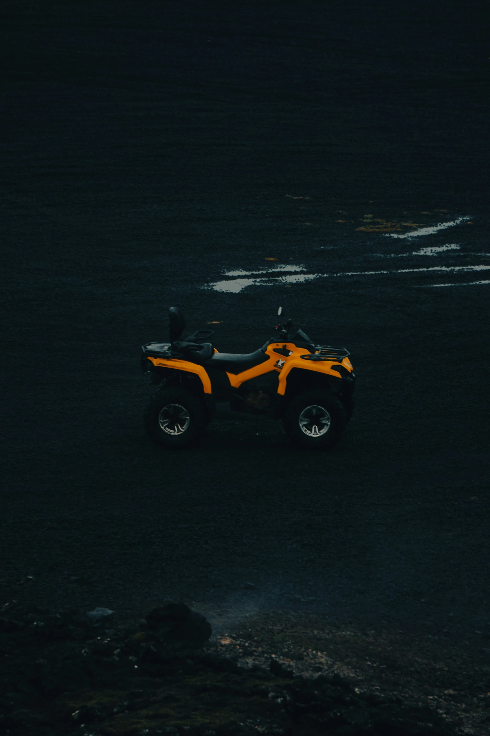 an orange and black four wheeler is in a dark area