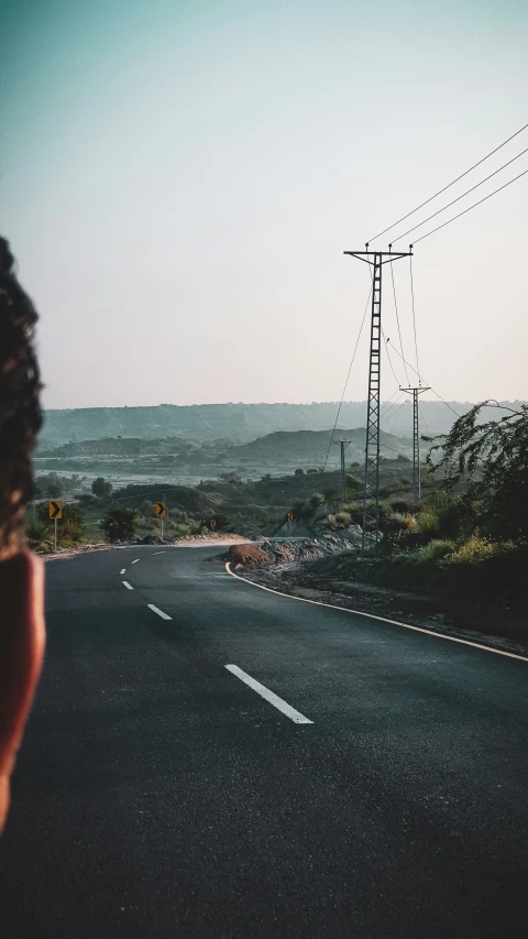 a person crossing the road in front of an electric pole