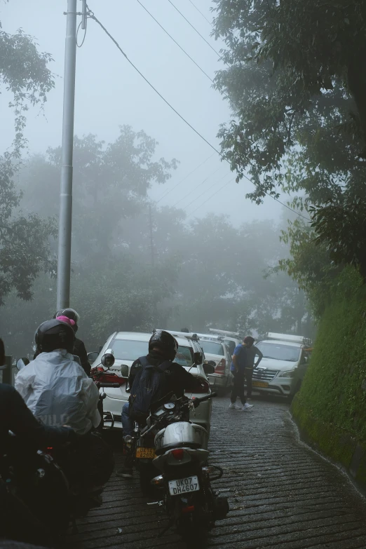 several motorcycles are stopped at a stop sign on a rain soaked street