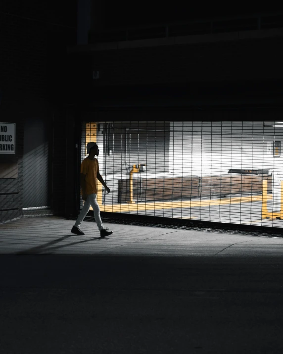 the man walks along an empty parking lot at night