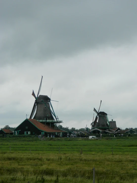 two windmills stand near each other on the grass