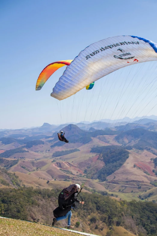 people parachuting on the top of a mountain with two parachutes