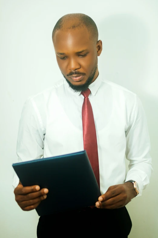 a man in a white shirt and red tie looking at a small computer screen