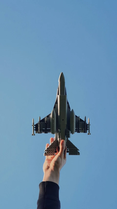 a hand holding an airplane in front of the blue sky