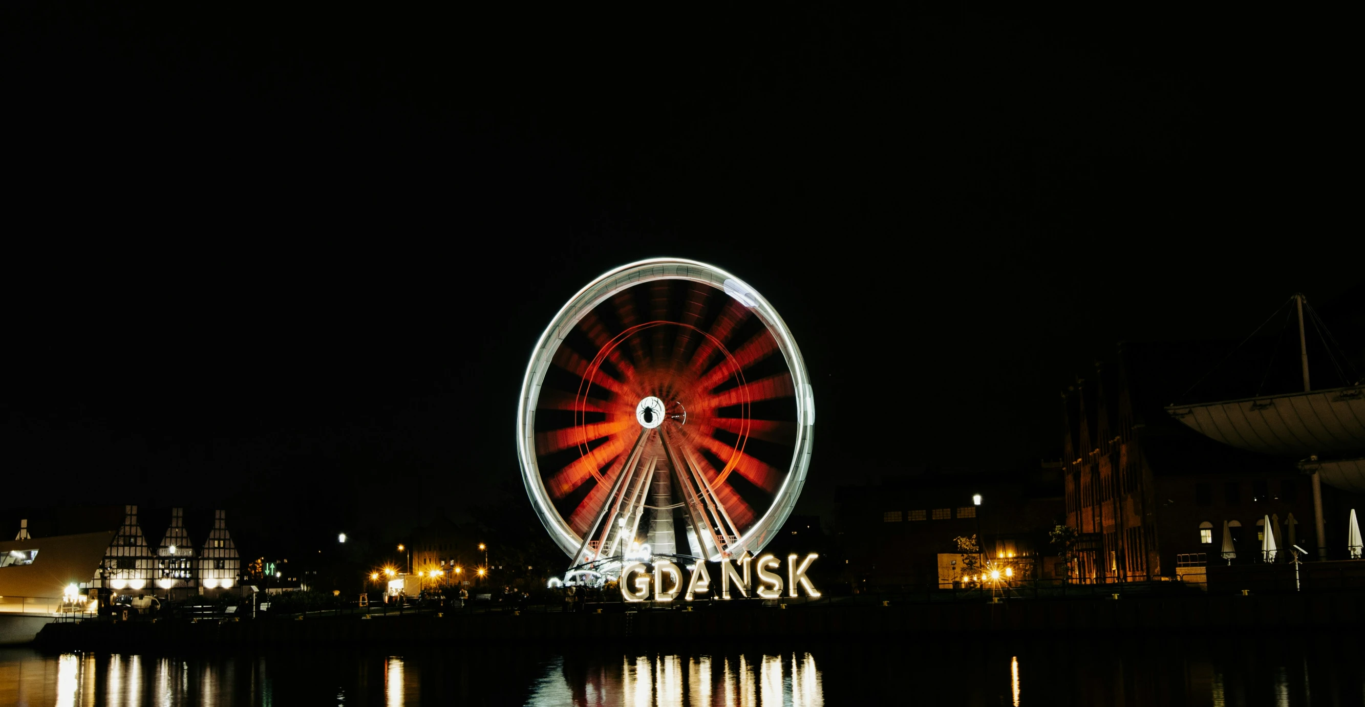 a big ferris wheel is on the water at night