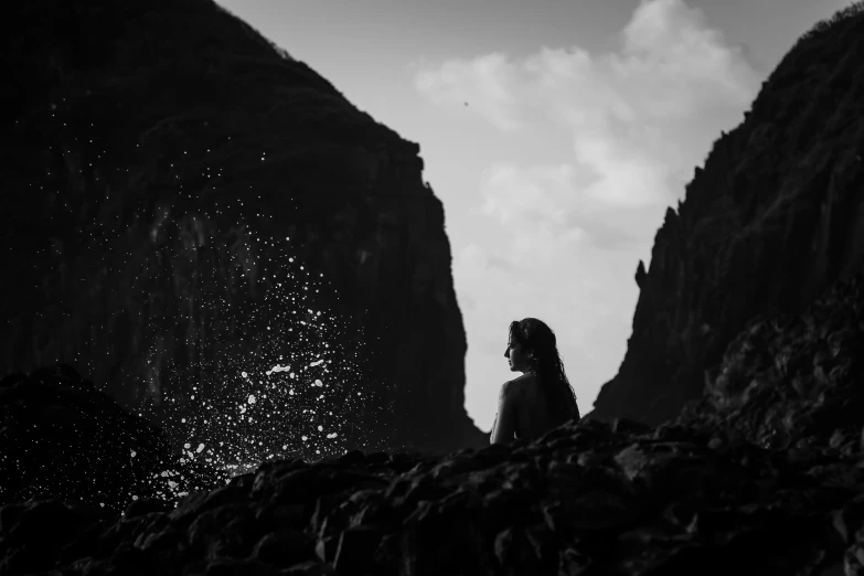 the silhouette of a person facing a rocky cliff in a black and white po