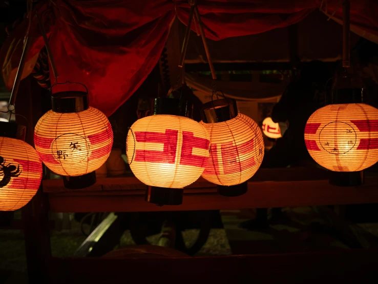 chinese lanterns are hanging on display under red curtains