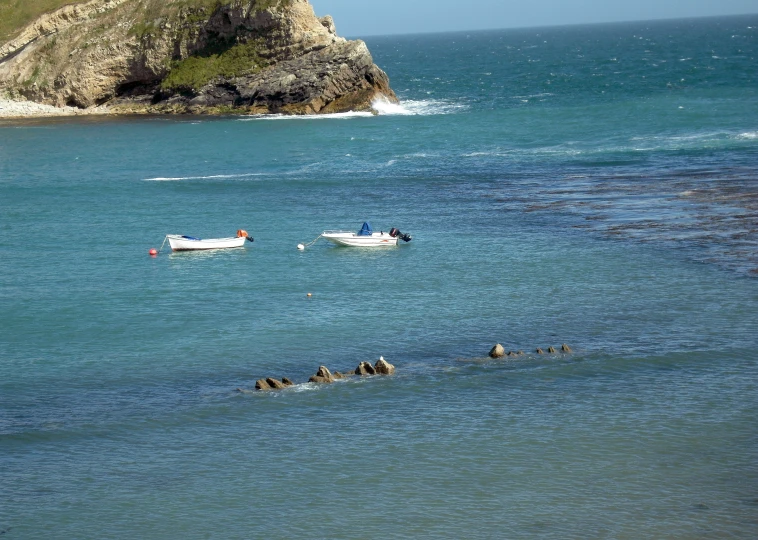 three boats in an ocean next to some rocks