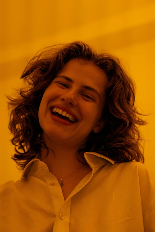 a woman laughing with a yellow background