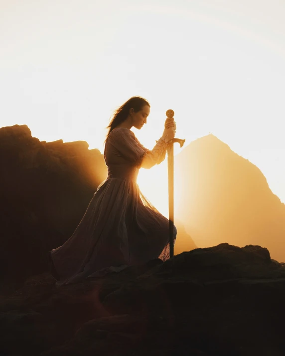 a woman is standing on a hill with her sword in hand