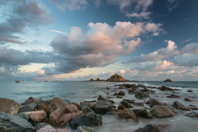 the beach has large rocks lined up to shore with a sky background