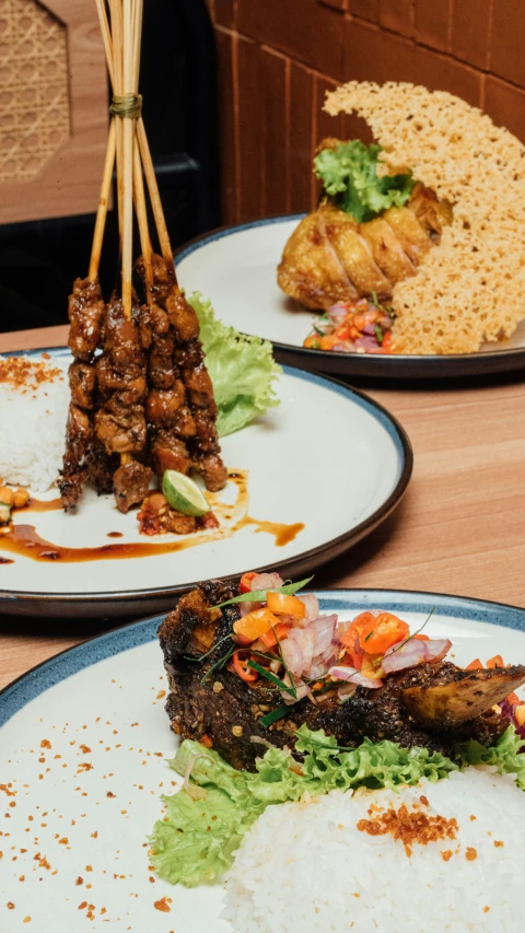 two plates with small food items and rice on them