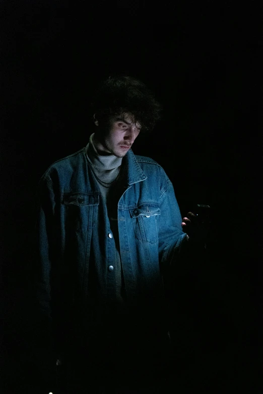 a man in the dark texting on his cell phone