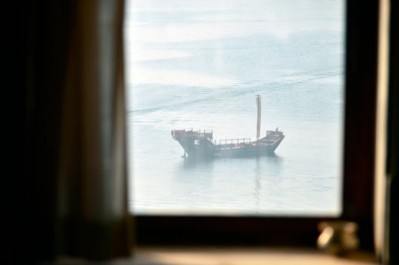 there is a boat on the water by itself from a window