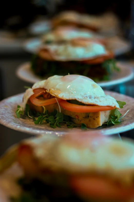 three plates holding sandwiches and eggs