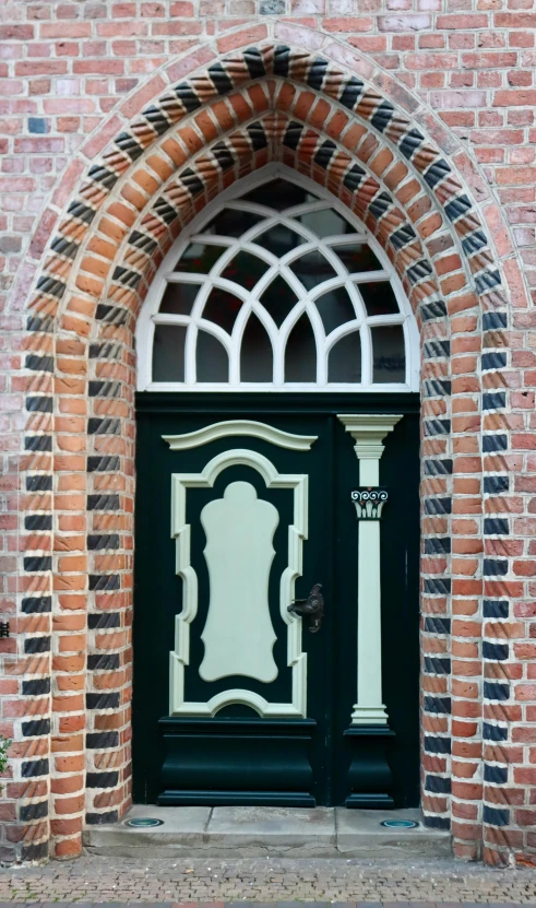 green wooden door and ornate arched stone arch on brick building