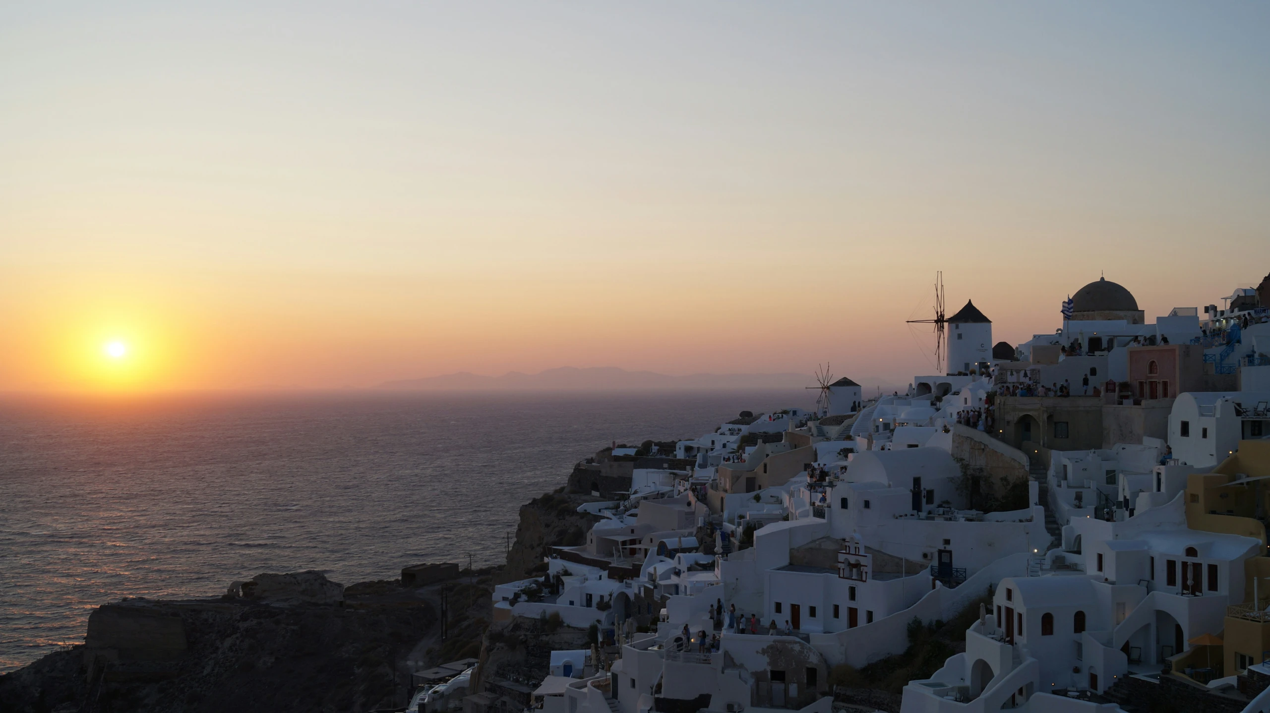 an image of the sun setting over a hillside with the sea