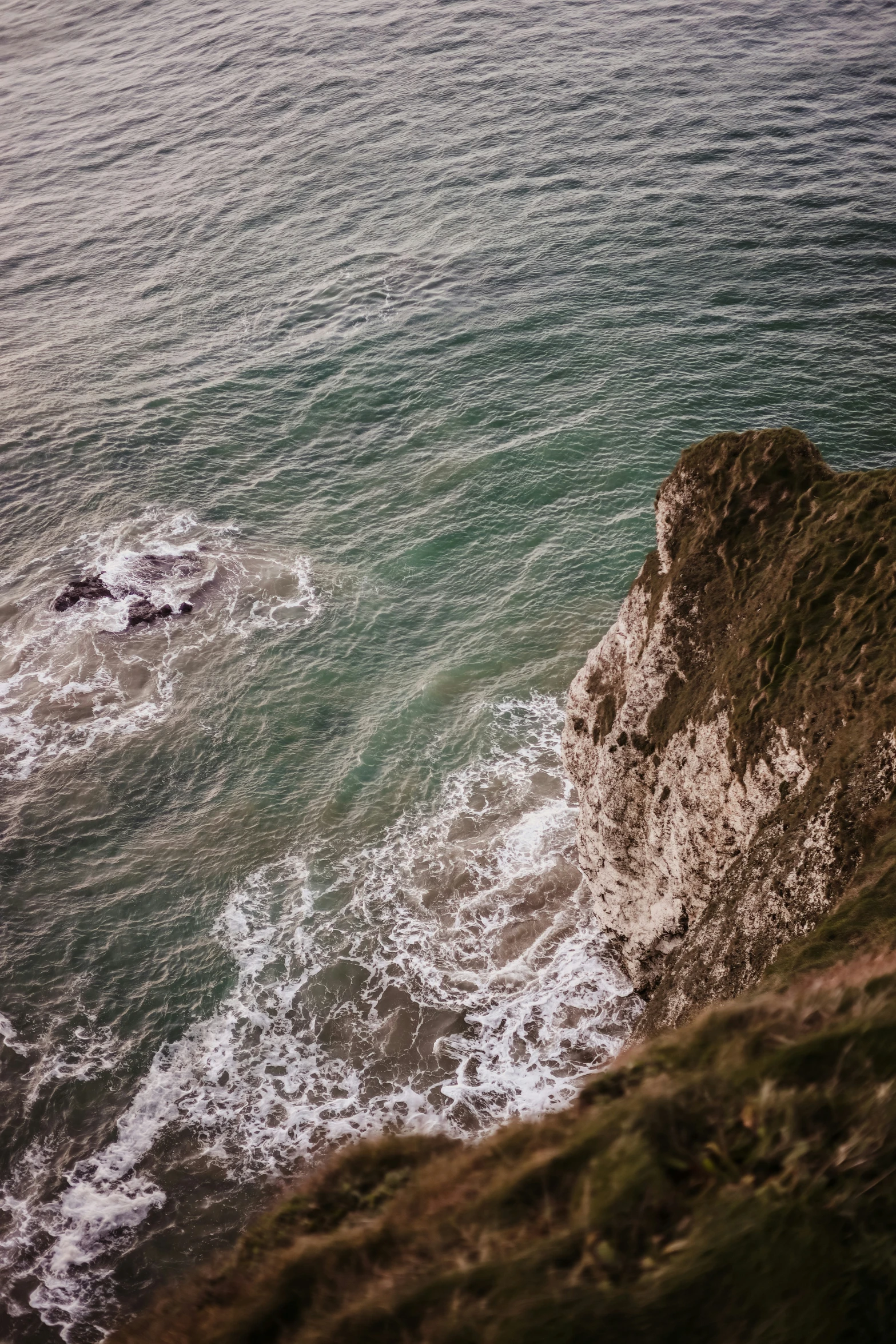 a person on top of a cliff and the ocean