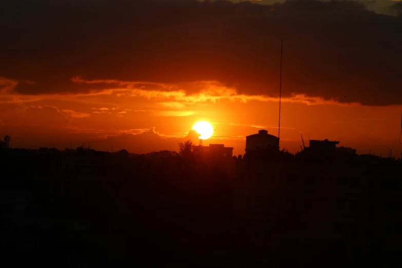 a setting sun over some building at dusk