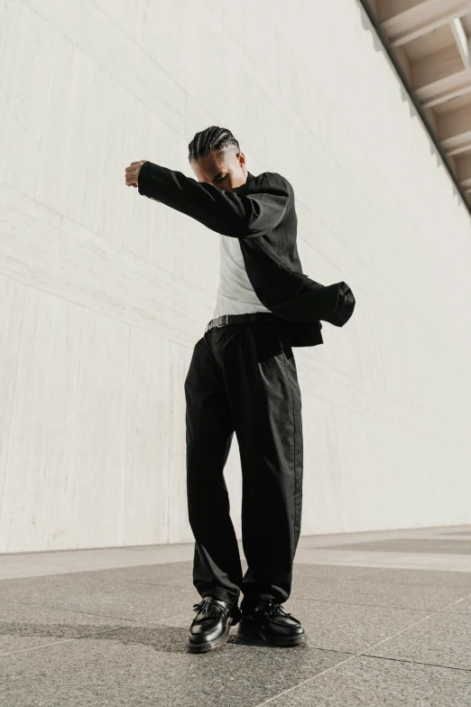 a man is standing on the concrete with one hand on his hip