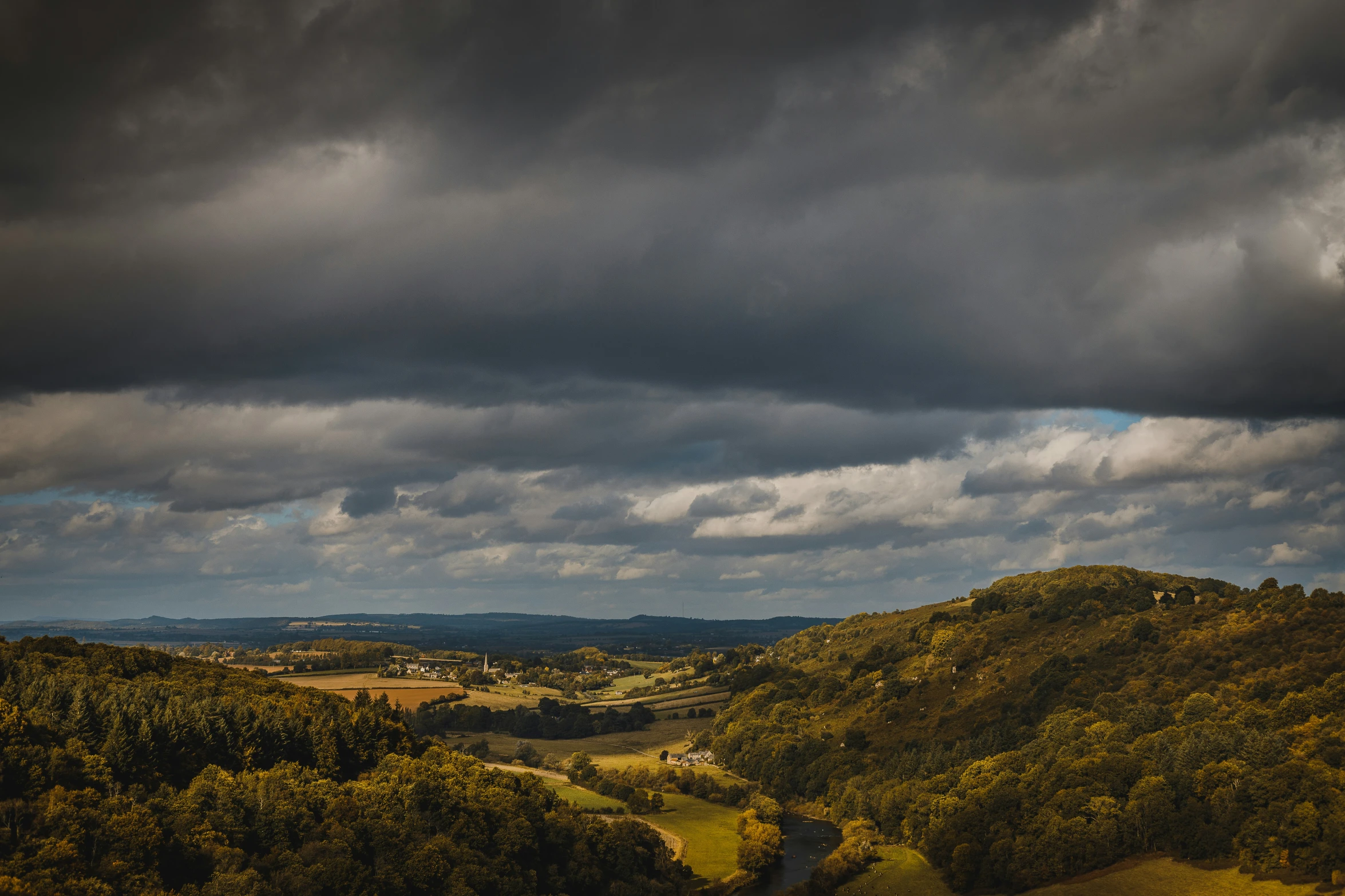 green hills, clouds and a forest below