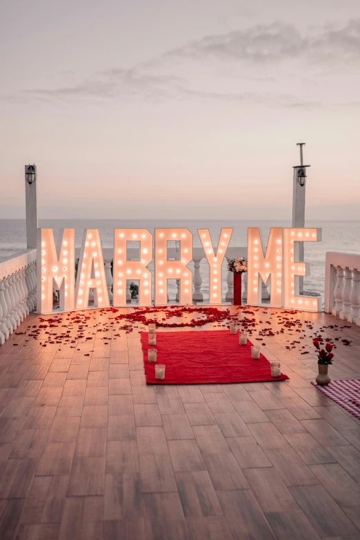 the word marry me lit up over a stage on the ocean