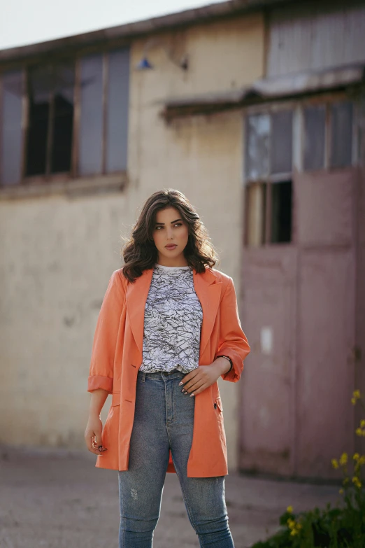 a girl in an orange blazer is standing on a street