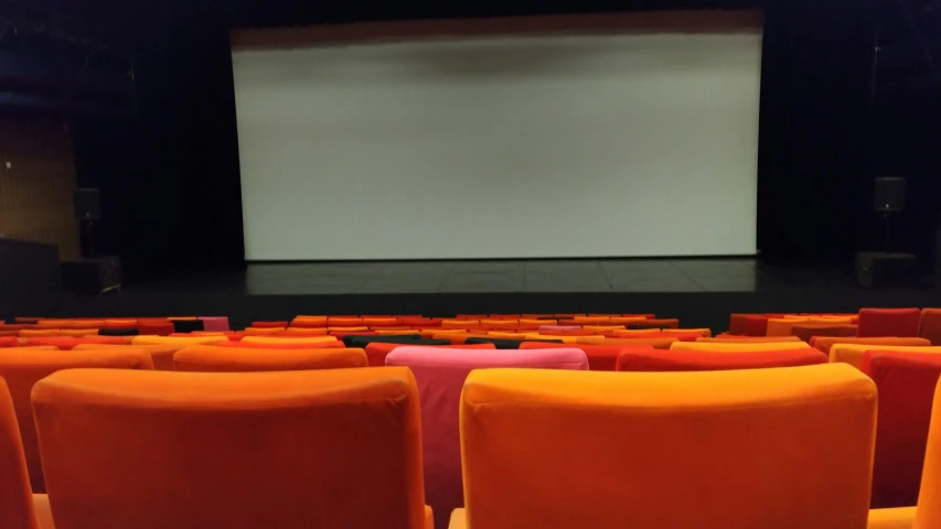 rows of orange and pink seating on large auditorium