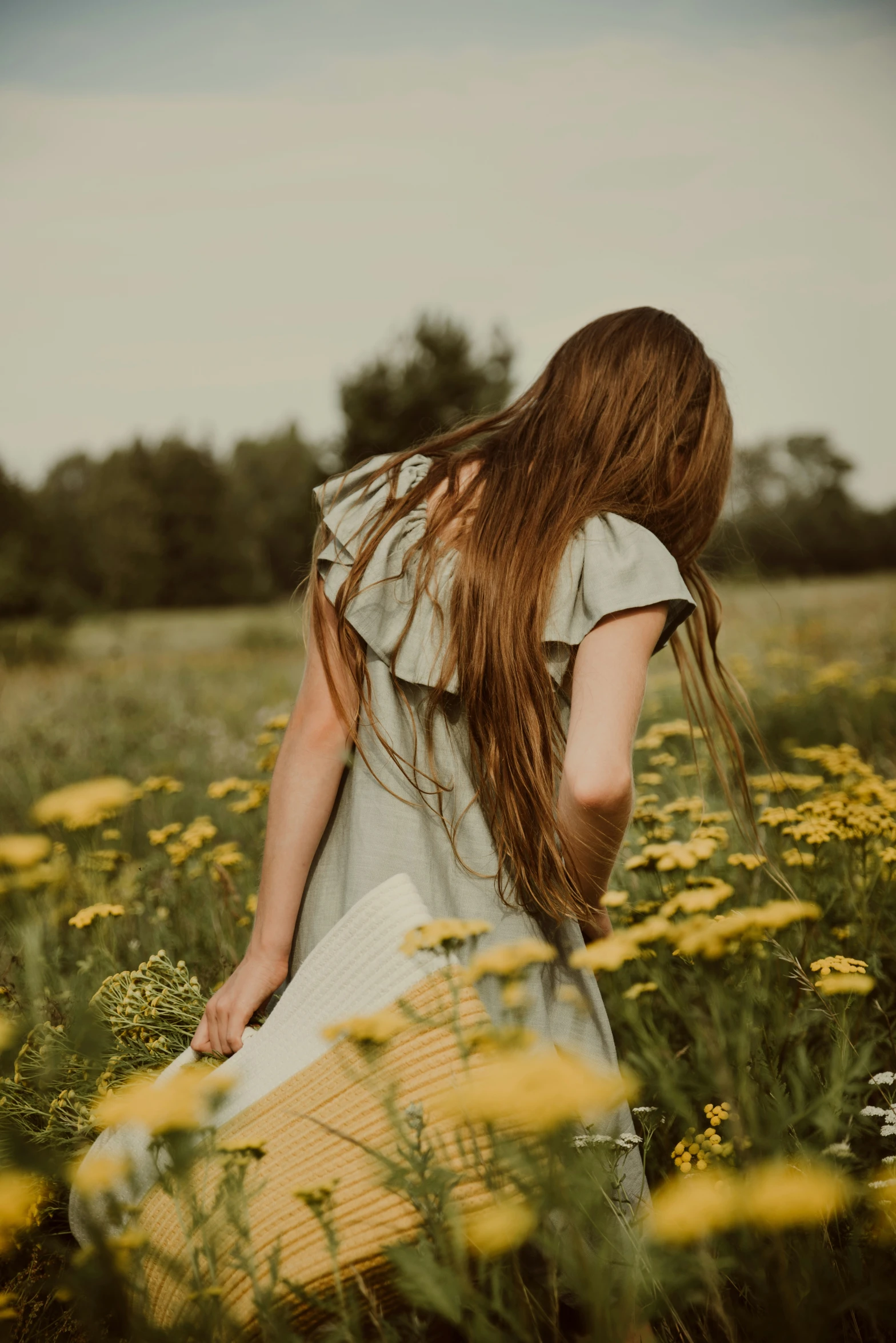 a woman is walking through a field with flowers