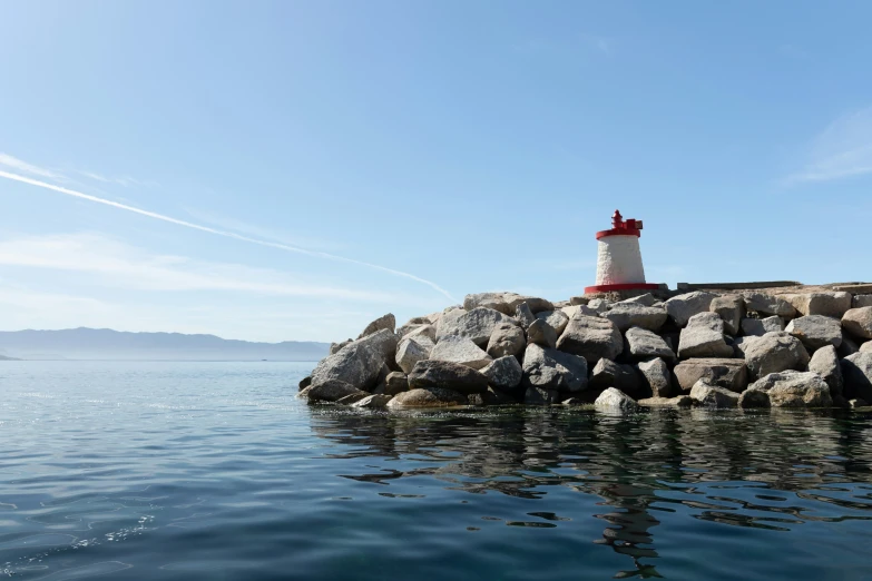 a red and white lighthouse sitting on top of some rocks
