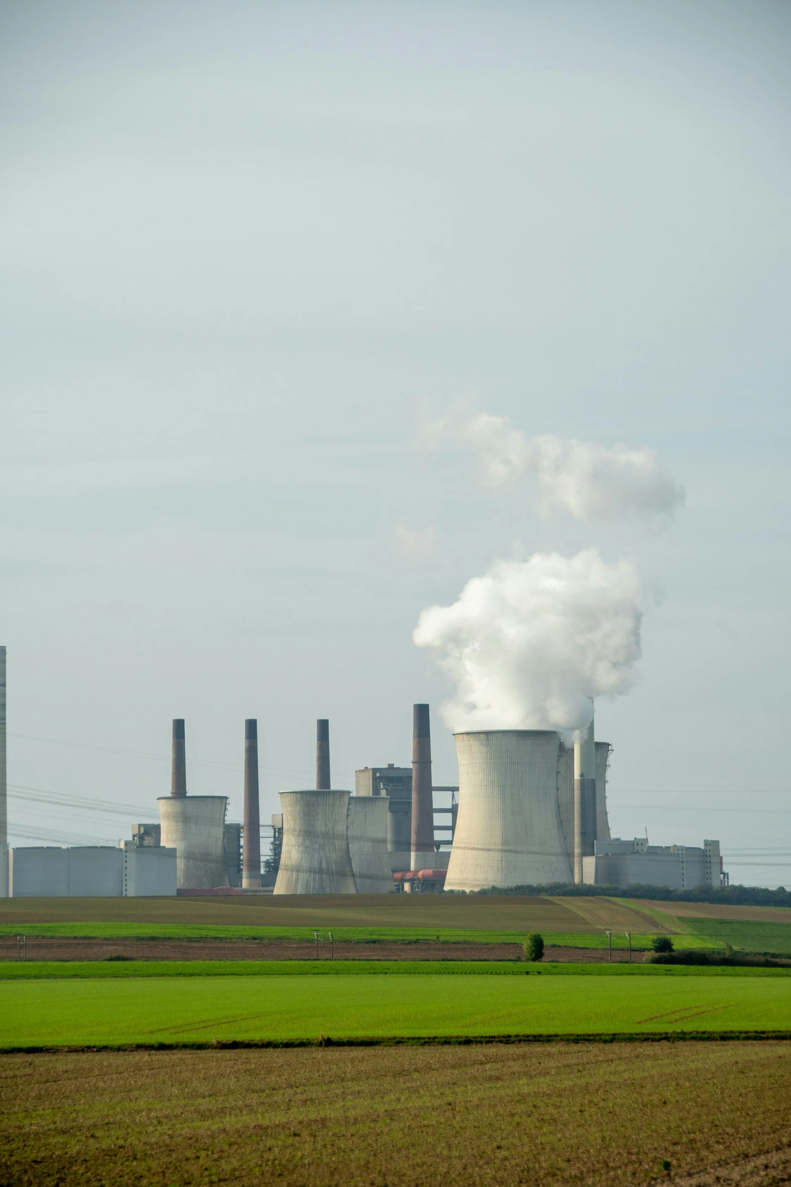 an industrial area with large smoke stacks and a green field