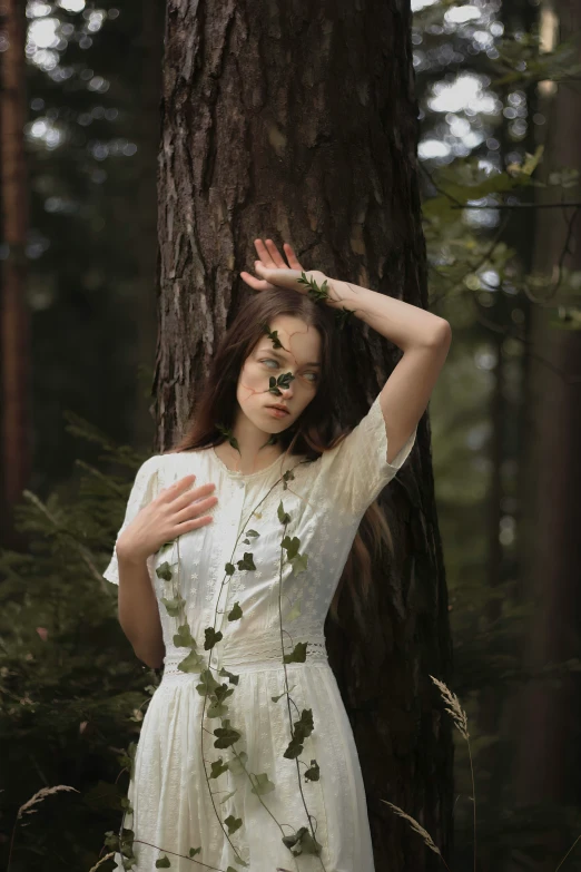 a woman with long hair standing by a tree