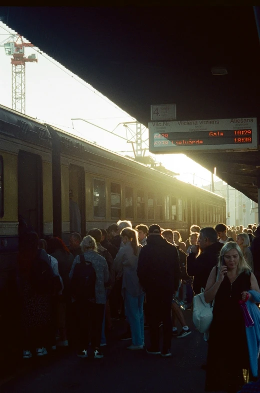 a large group of people are waiting to get onto the train