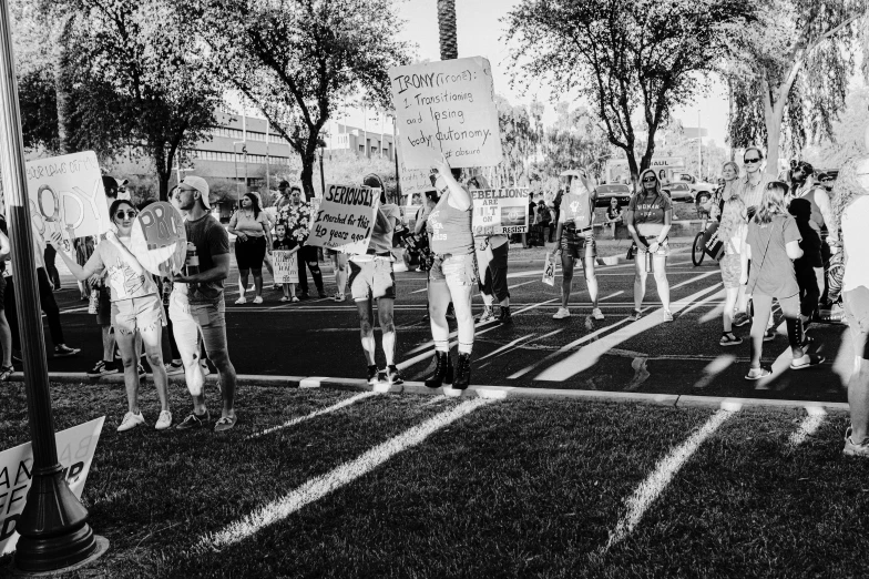 a group of people holding signs standing on top of a field