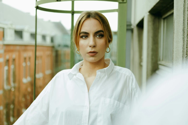 an attractive young woman wearing all white standing near a window