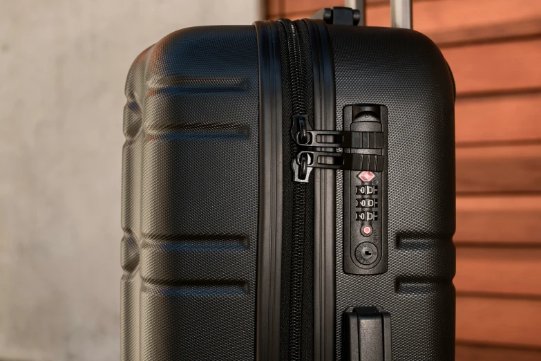 black suitcase in front of wall with writing on handle