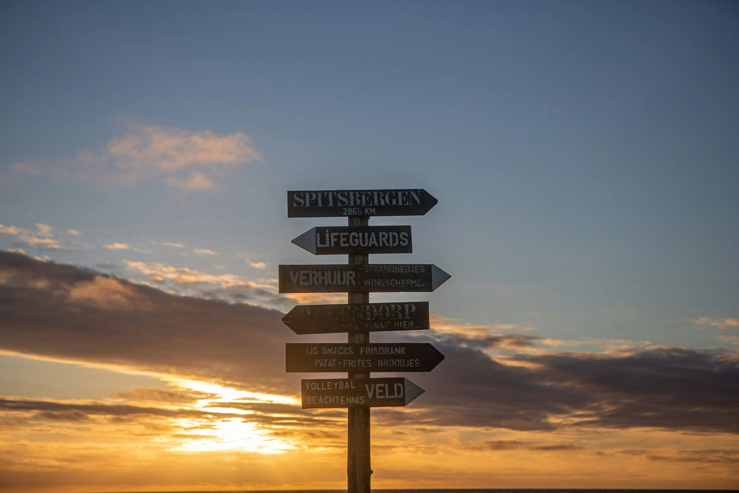 a sign on the side of a hill at sunset